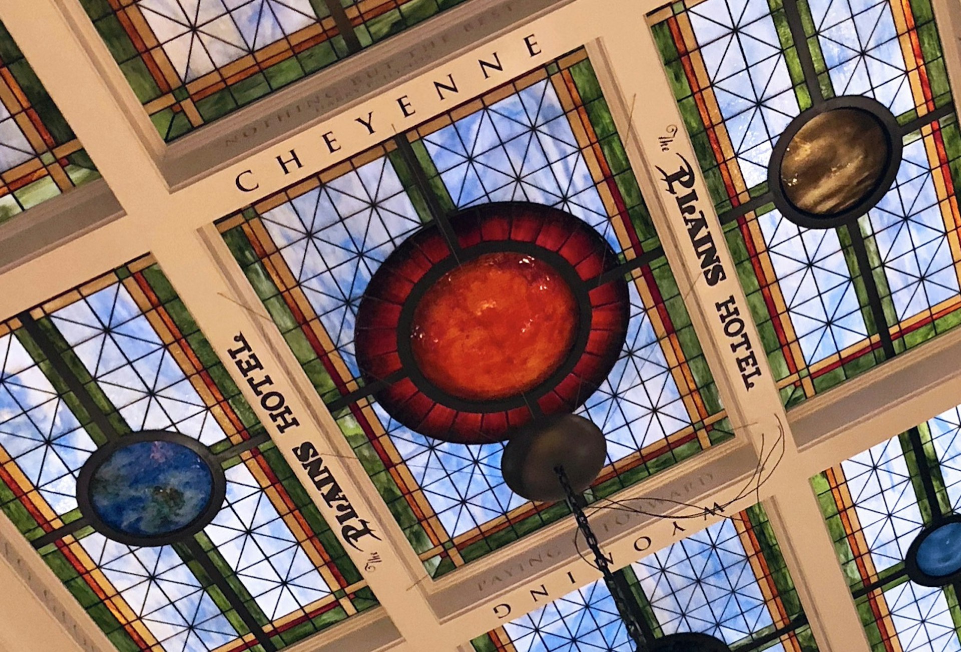 The words 'Cheyenne', 'Wyoming' and 'The Plains Hotel' surround a rectangular stained glass ceiling, with blue and red panes of glass and a circle motif © Dave Parfitt / Lonely Planet