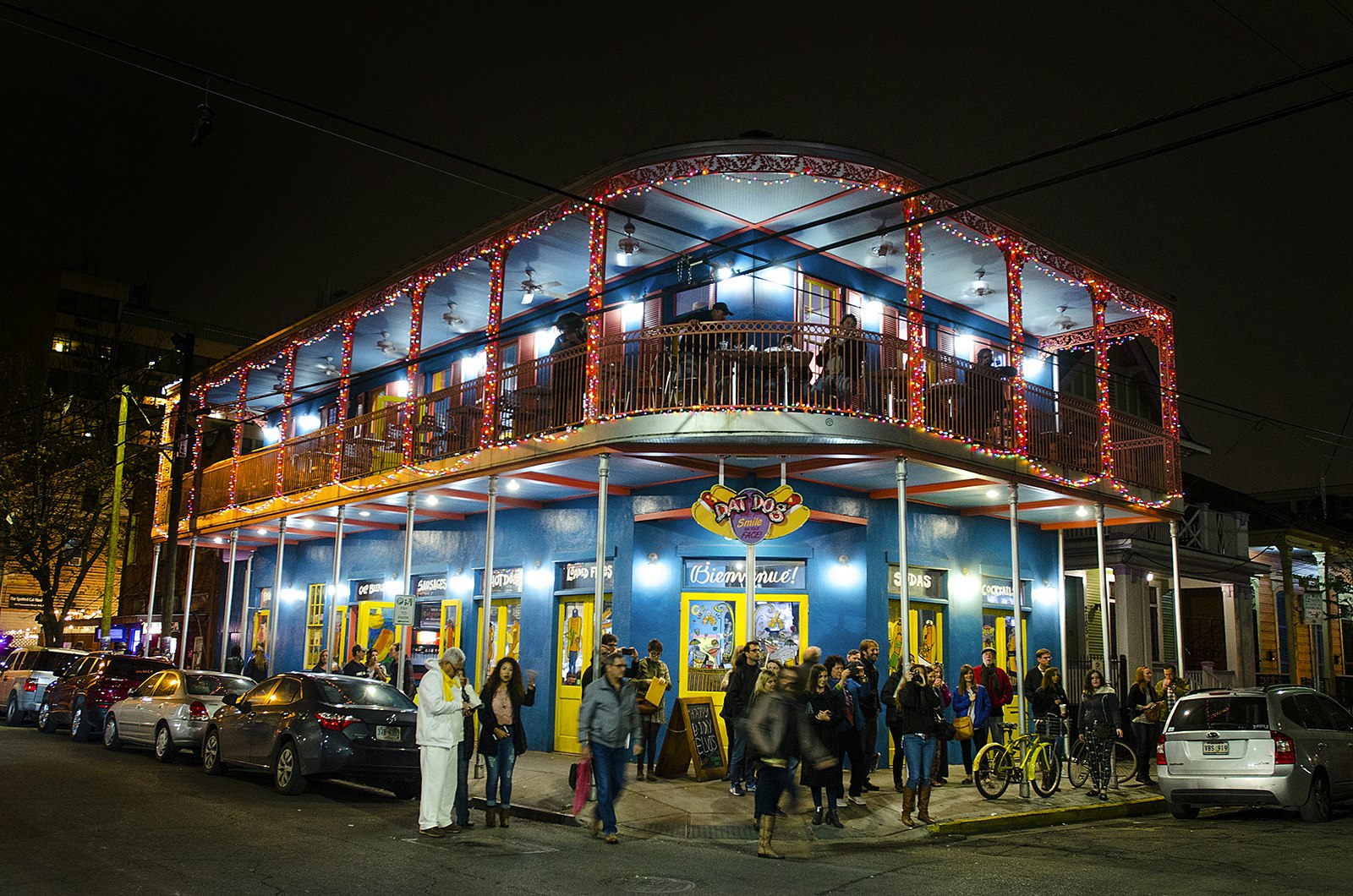 Two-story 19th-century building in New Orleans with wrought-iron railings is illuminated at night 