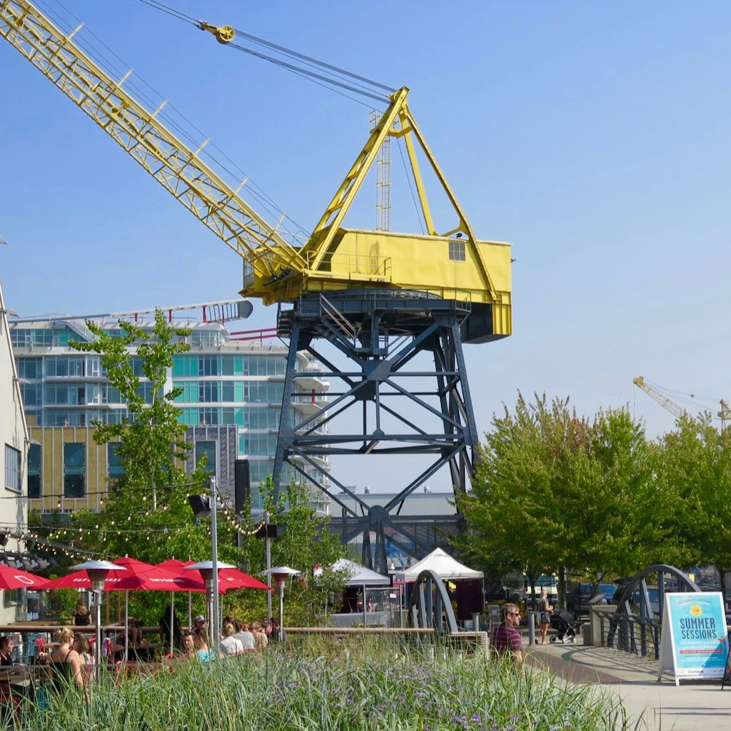 A massive yellow crane rises above a park with umbrellas and a building in the background © John Lee / Lonely Planet