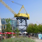 A massive yellow crane rises above a park with umbrellas and a building in the background © John Lee / Lonely Planet