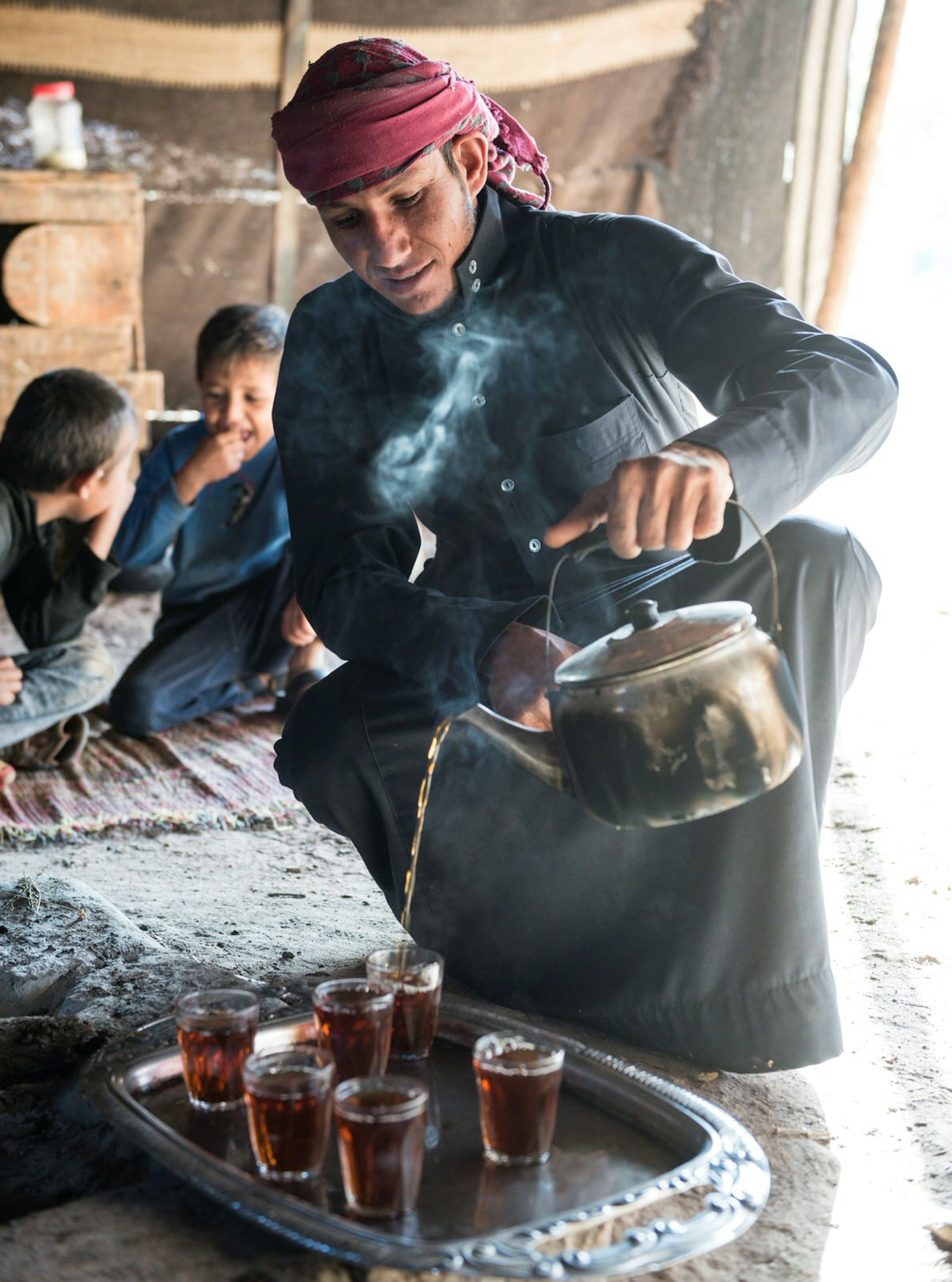 A Bedouin pours tea from a kettle 