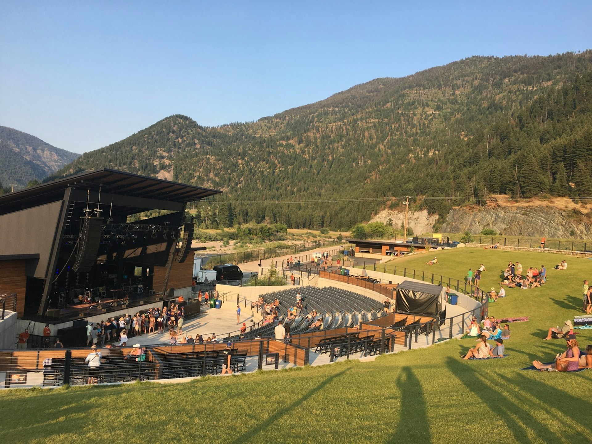 A large open-air amphitheater with seats and a grassy lawn backs up to a view of mountains and a river © Jay Gentile / Lonely Planet