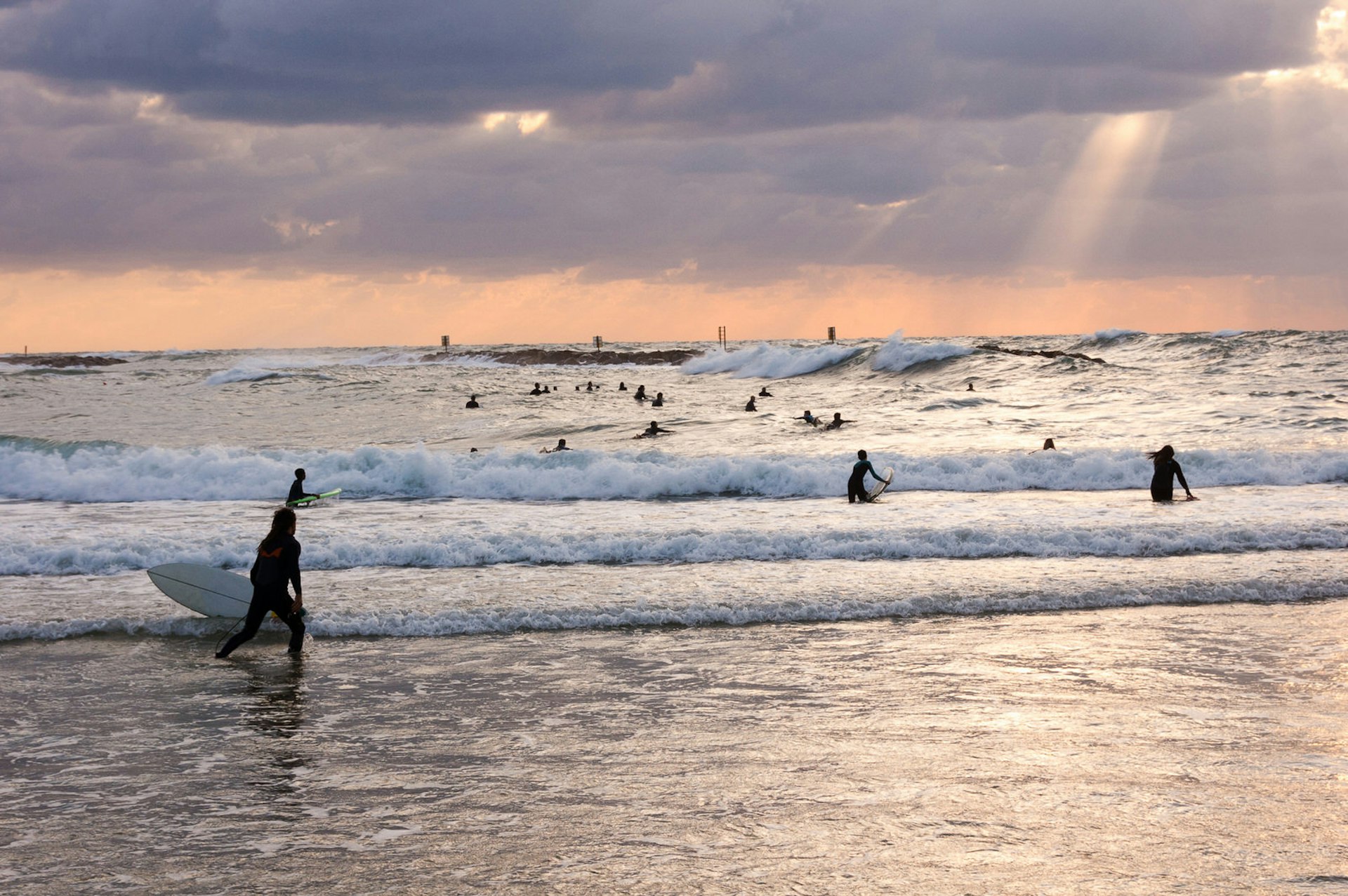 Silhouetted surfers at sunset in the Mediterranean Sea, Tel Aviv.