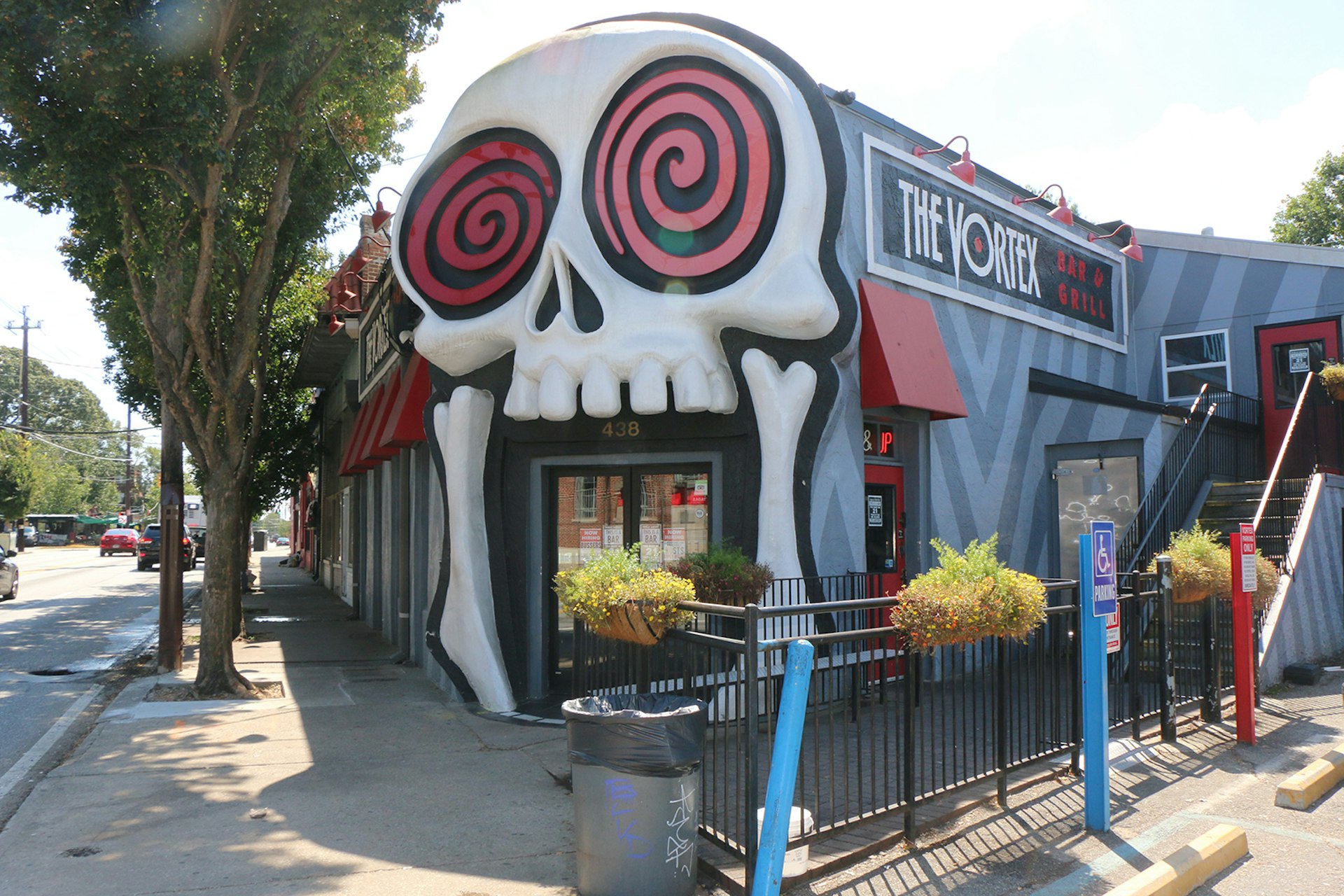 Building facade with google-eyed skull on the front, home to Vortex in Atlanta, on a sunny day