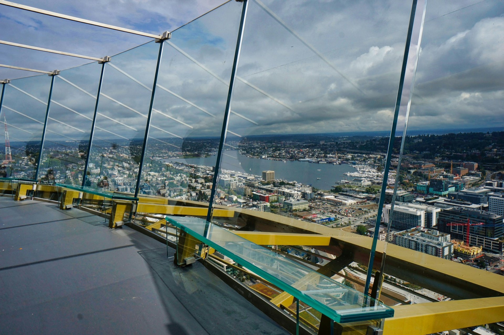 Curved glass panels surround an observation deck hundreds of feet in the sky as the city unfolds beyond 