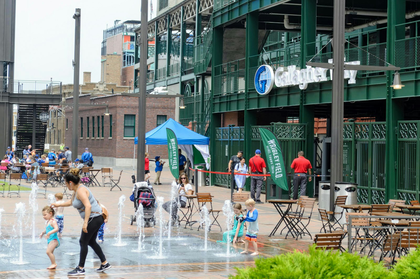 a woman and child play in outdoor fountains near Wrigley Field in Chicago