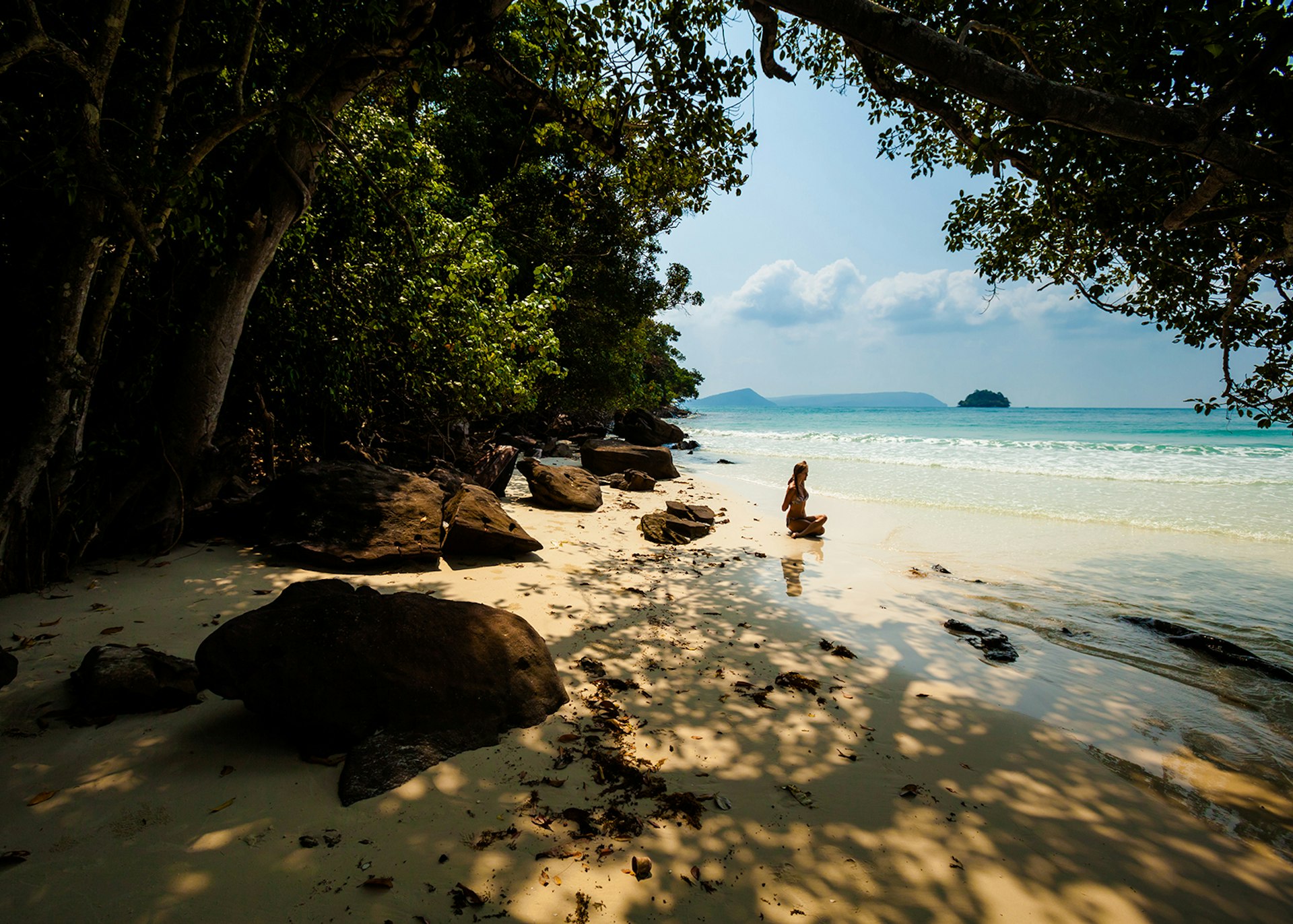 Woman sitting on tropical beach doing yoga
