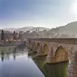 The symmetrical arches of the Mehmet Paša Sokolović Bridge, with the town of Višegrad in the background, shrouded in mist
