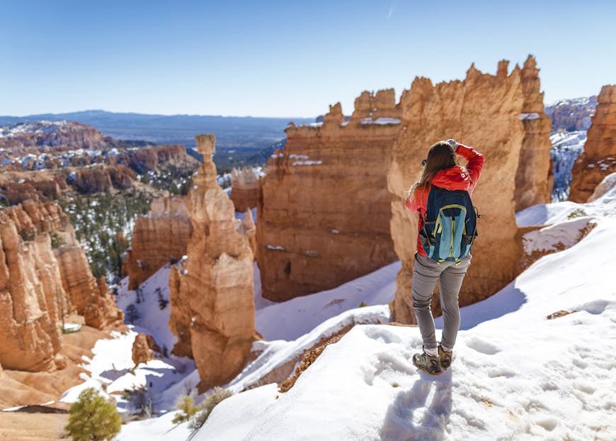 A hiker takes a picture of a snow-blanketed Bryce Canyon