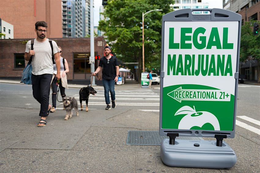 People pass a Legal Marijuana shop sign late in the day in Seattle, Washington