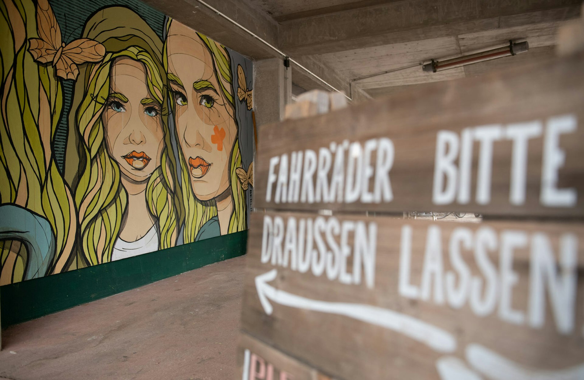 Free Berlin - Street art artist El Bocho painted an artwork inside an underpass at the Holzmarktstrasse. The artwork is part of the 'Berlin Mural Fest'. Artists designed numerous facades in the city according to their ideas. The image is of two blonde female faces, with bold linework on a teal background.