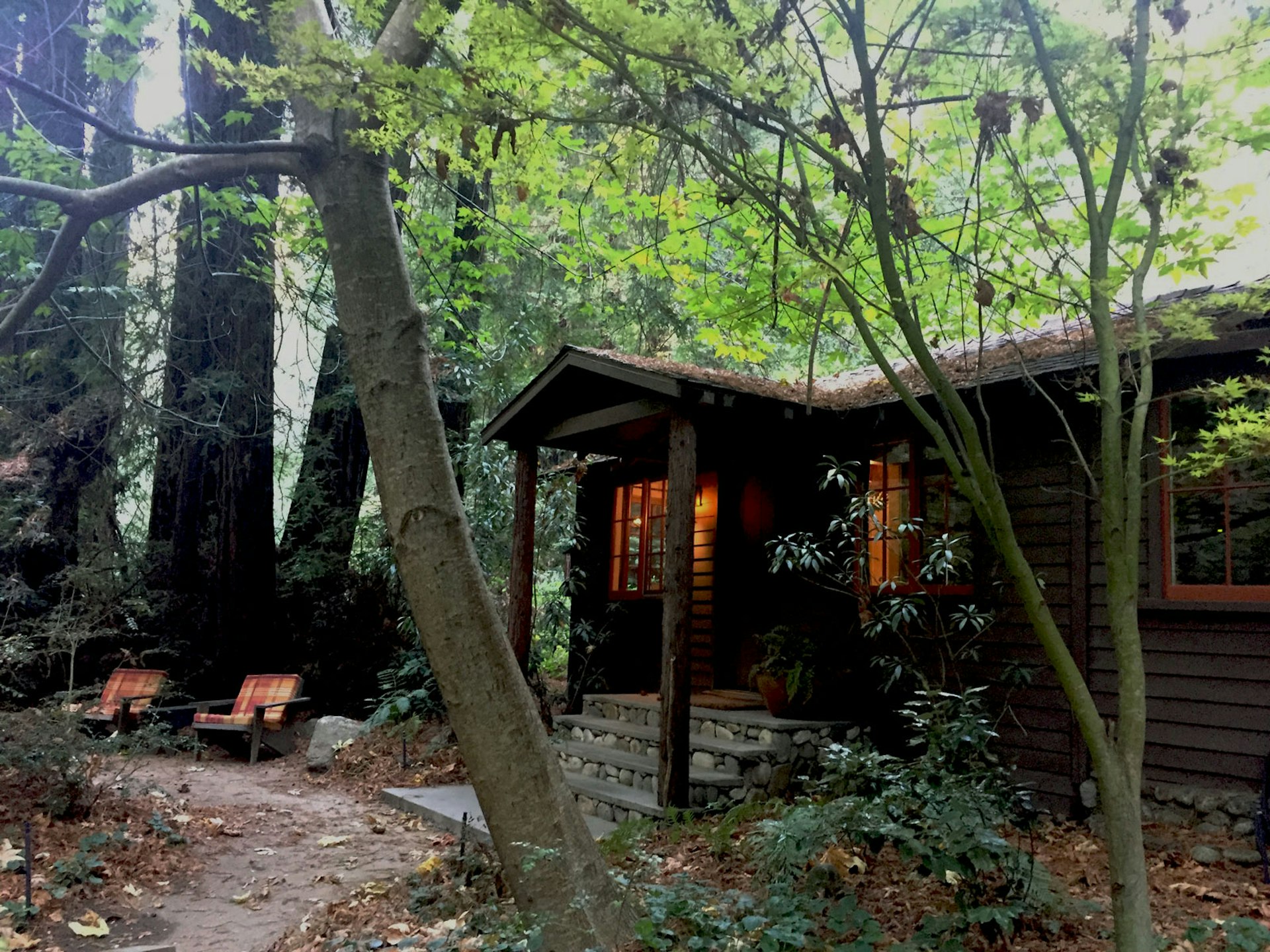 A cabin in the woods with two chairs in front