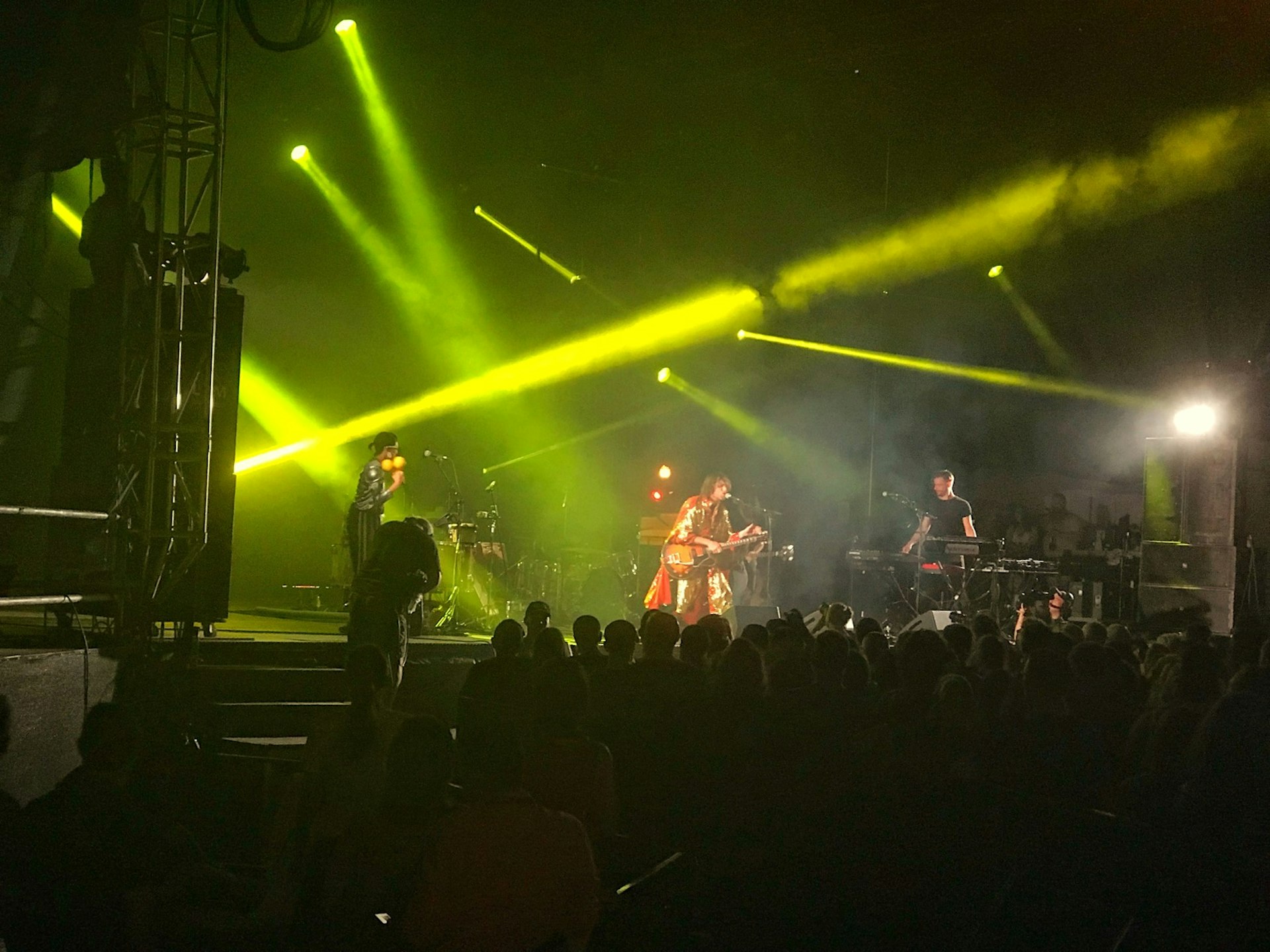 Yellow laser lights illuminate a smoky atmosphere on stage at a music festival