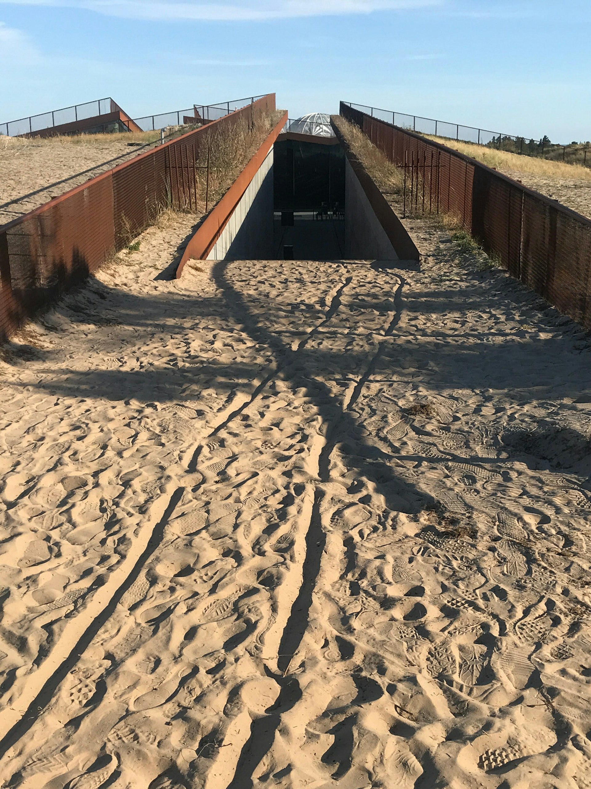 A sandy walkway leading to the underground entrance at the Tirpitz Bunker Museum © Abigail Blasi / Lonely Planet
