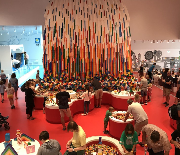 Adults and children playing with brightly-coloured Lego bricks inside the Lego House in Billund © Abigail Blasi / Lonely Planet