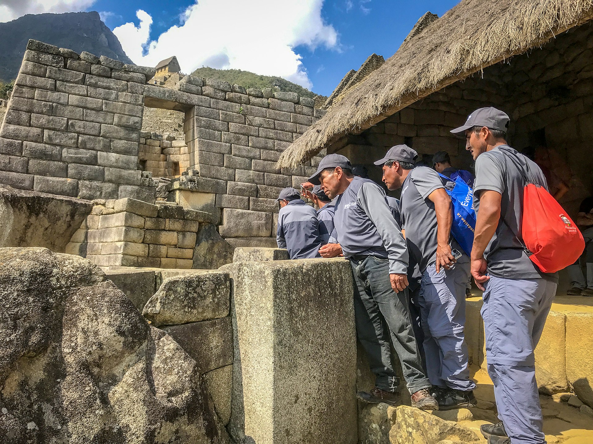 Men peer over a rock ledge at Machu Picchu