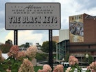 Sign reading "welcome to Akron Ohio, home of the Black Keys' surrounded by hydrangeas with a stadium in the background