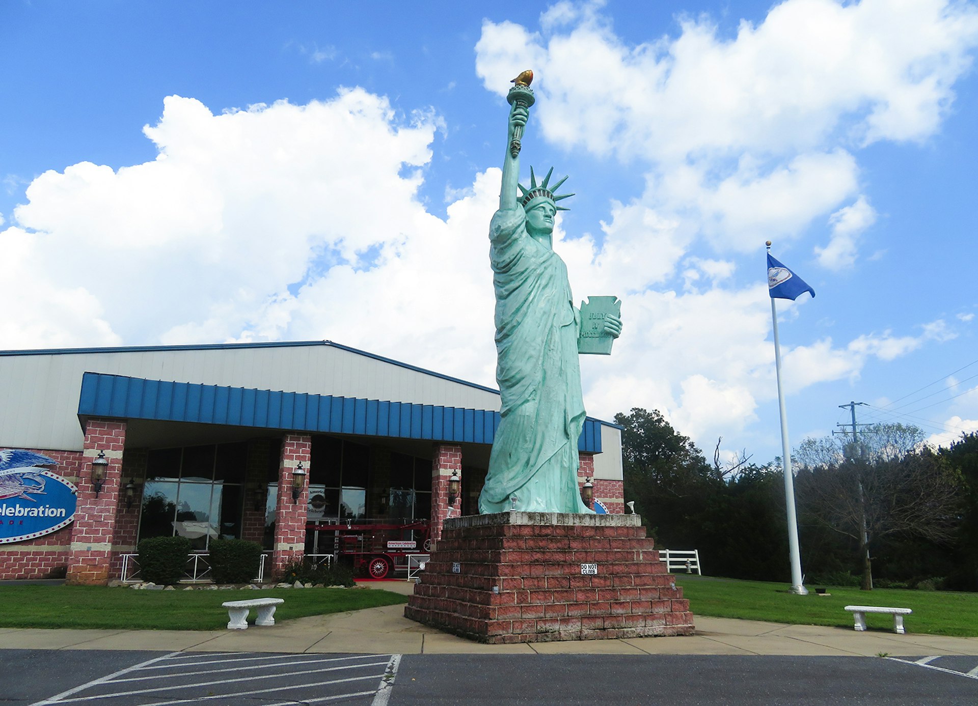 An approximately 30-foot replica of the statue of liberty sits outside the Americana Celebration museum on a sunny day