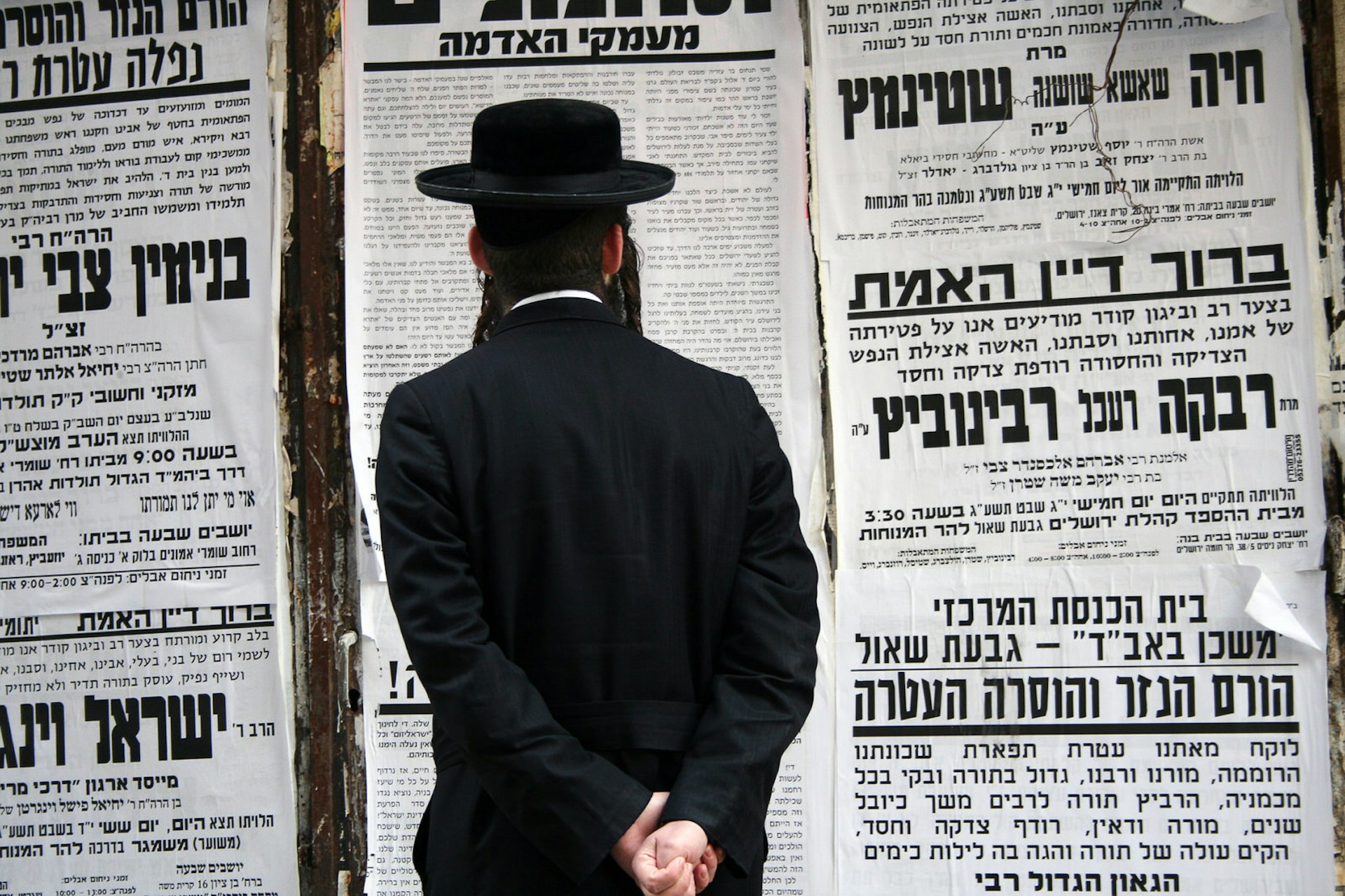 Man dressed in traditional clothing stands reading on the street in the ultra-orthodox area of Jerusalem, Mea Shearim 