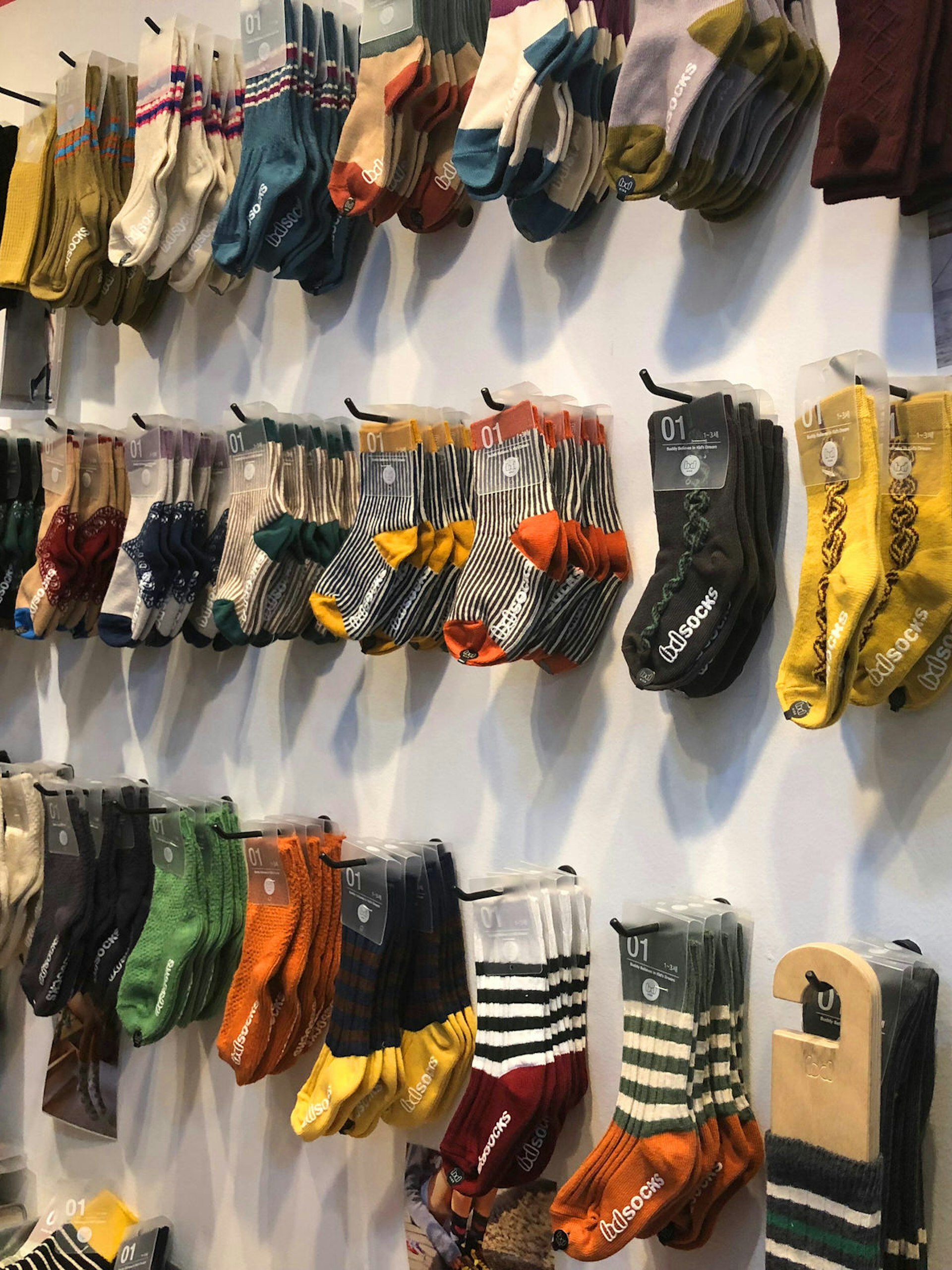 Several racks of socks in yellow and grey, orange, and muted tones and stripes