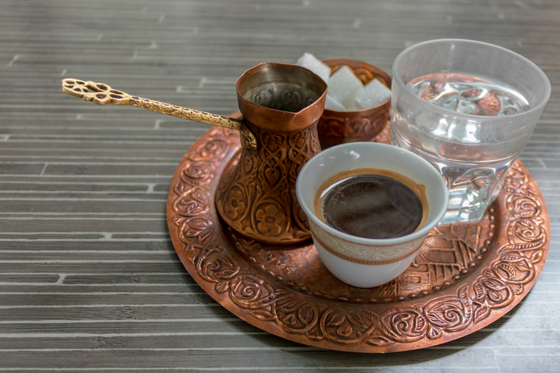 A cup of traditional Bosnian coffee with a glass of water and sugar lumps