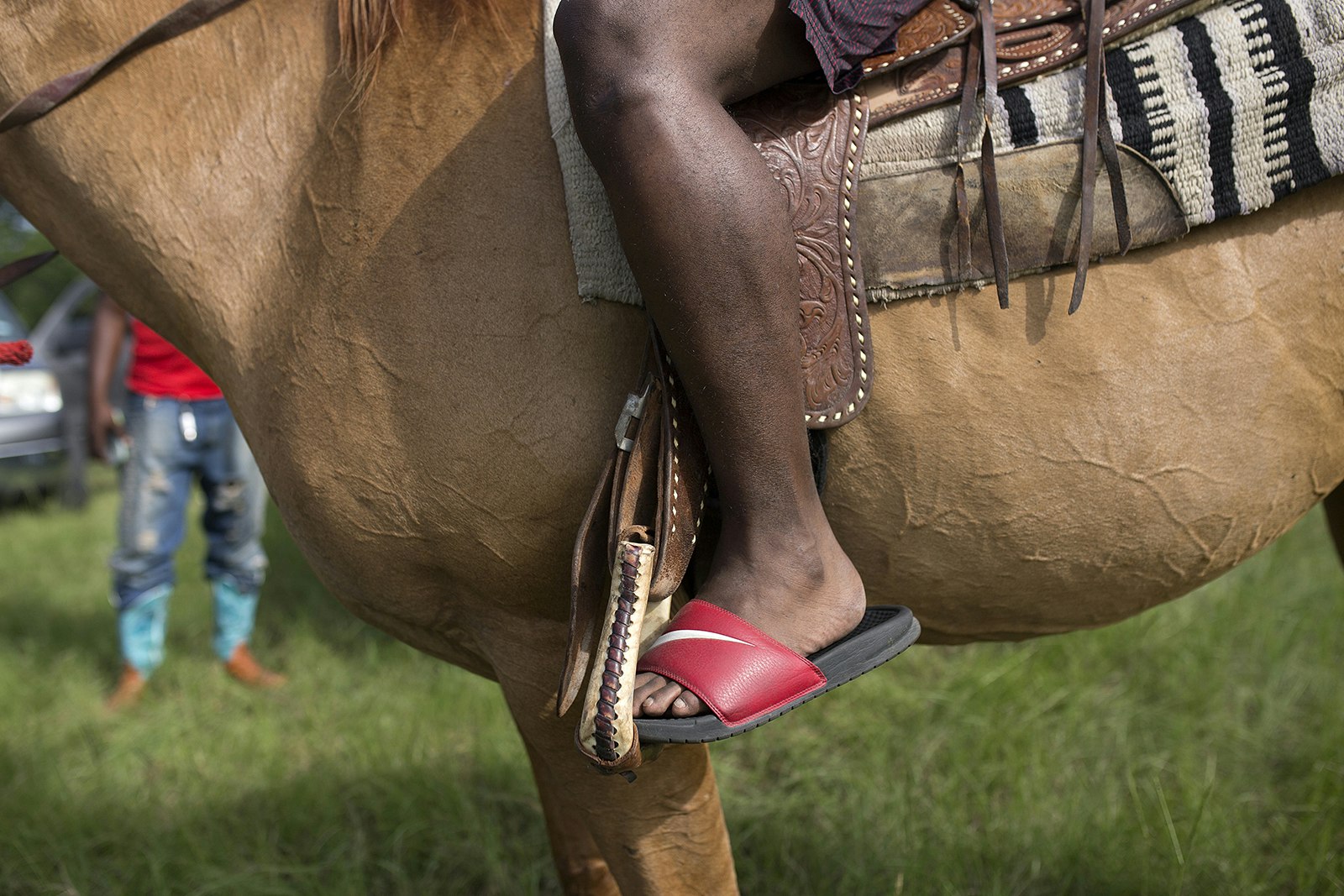 close up of saddled brown horse with a red slide sandal in the stirrups