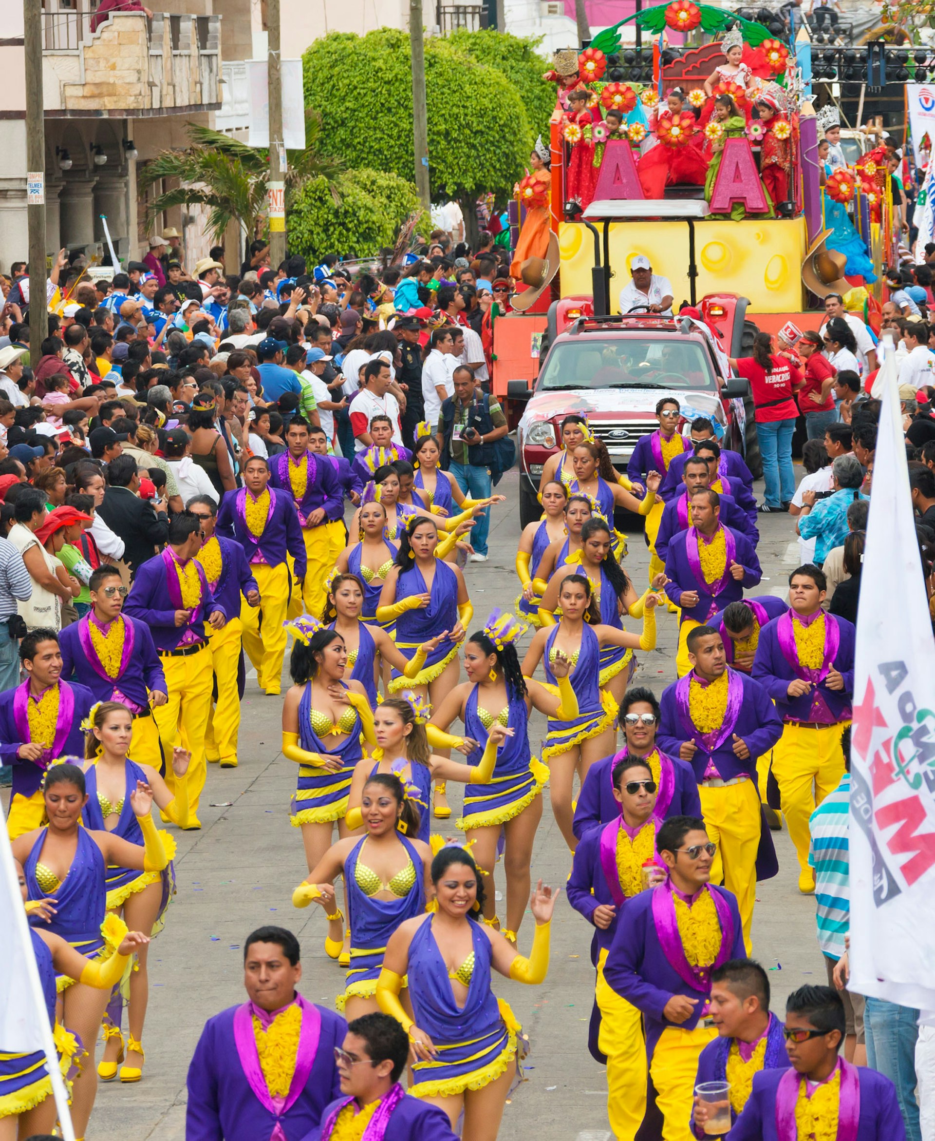 People in yellow and purple costumes dance in a parade