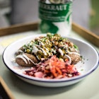 A tin dish full of potatoes, red cabbage coleslaw and beans drizzled with a white dressing.
