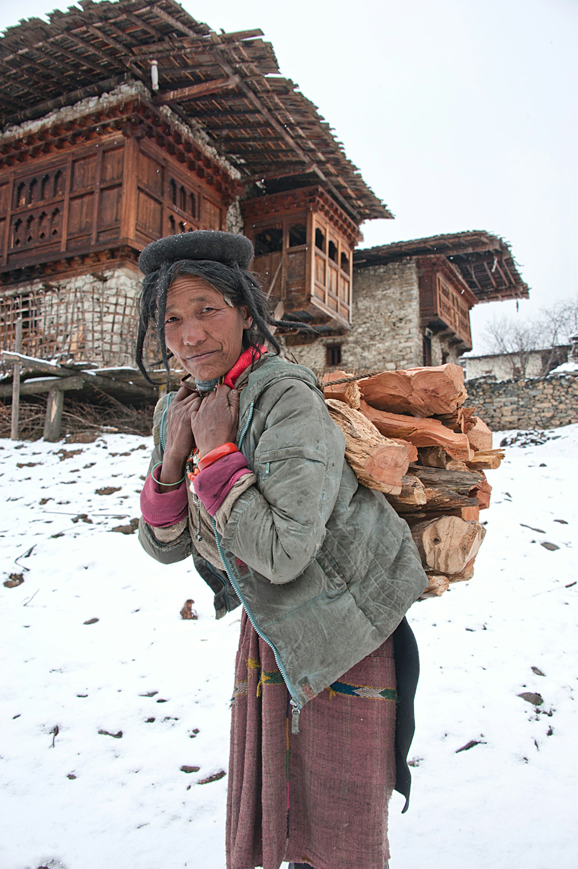 Brokpa woman carrying firewood in the snow © Diana Mayfield / Getty Images