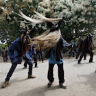 Three men in masks with long beards swing the hair around