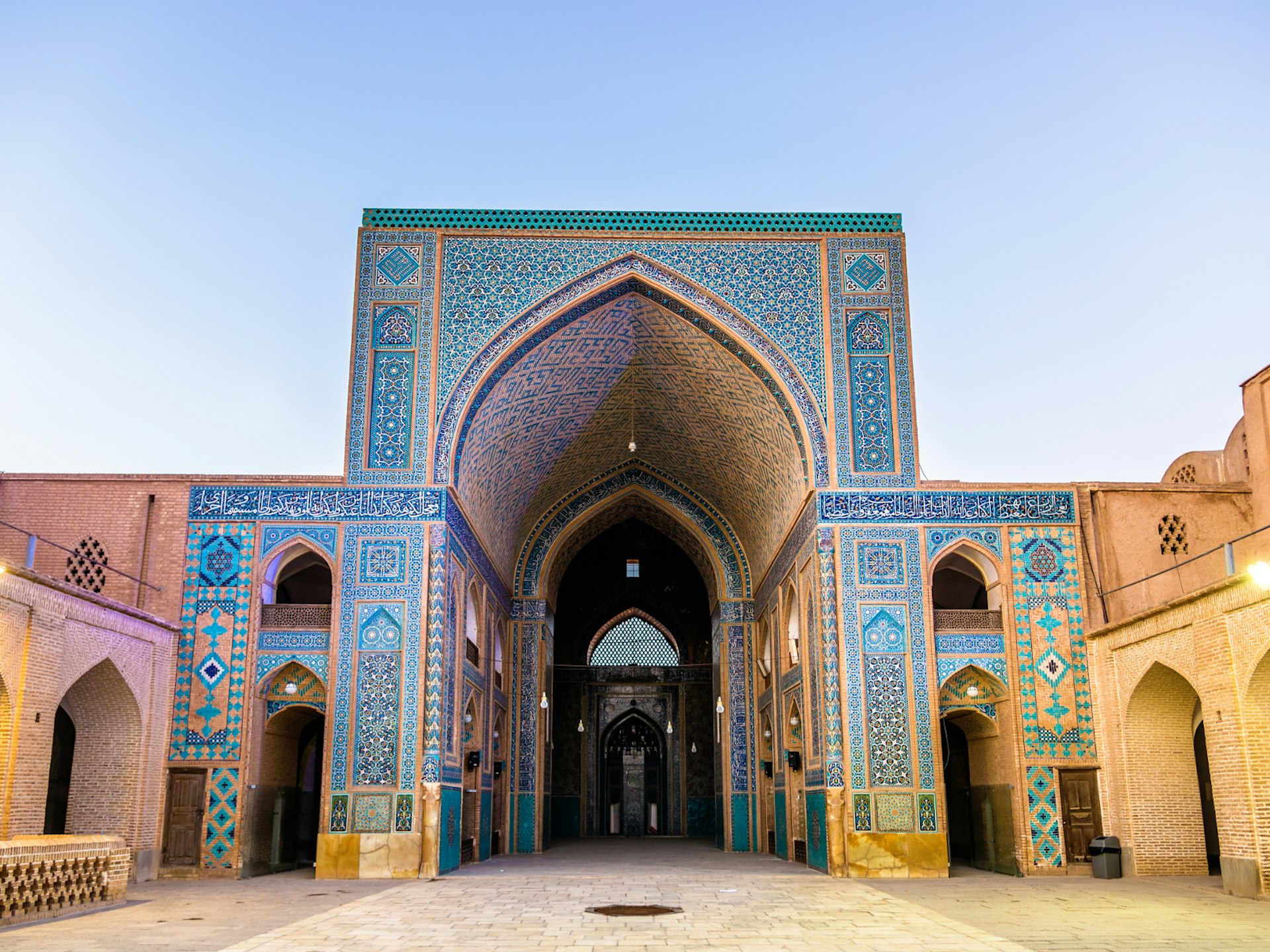 Courtyard of a mosque in the Iranian city of Yazd. The building is covered in intricate tile patters, predominantly shades of blue with some yellow