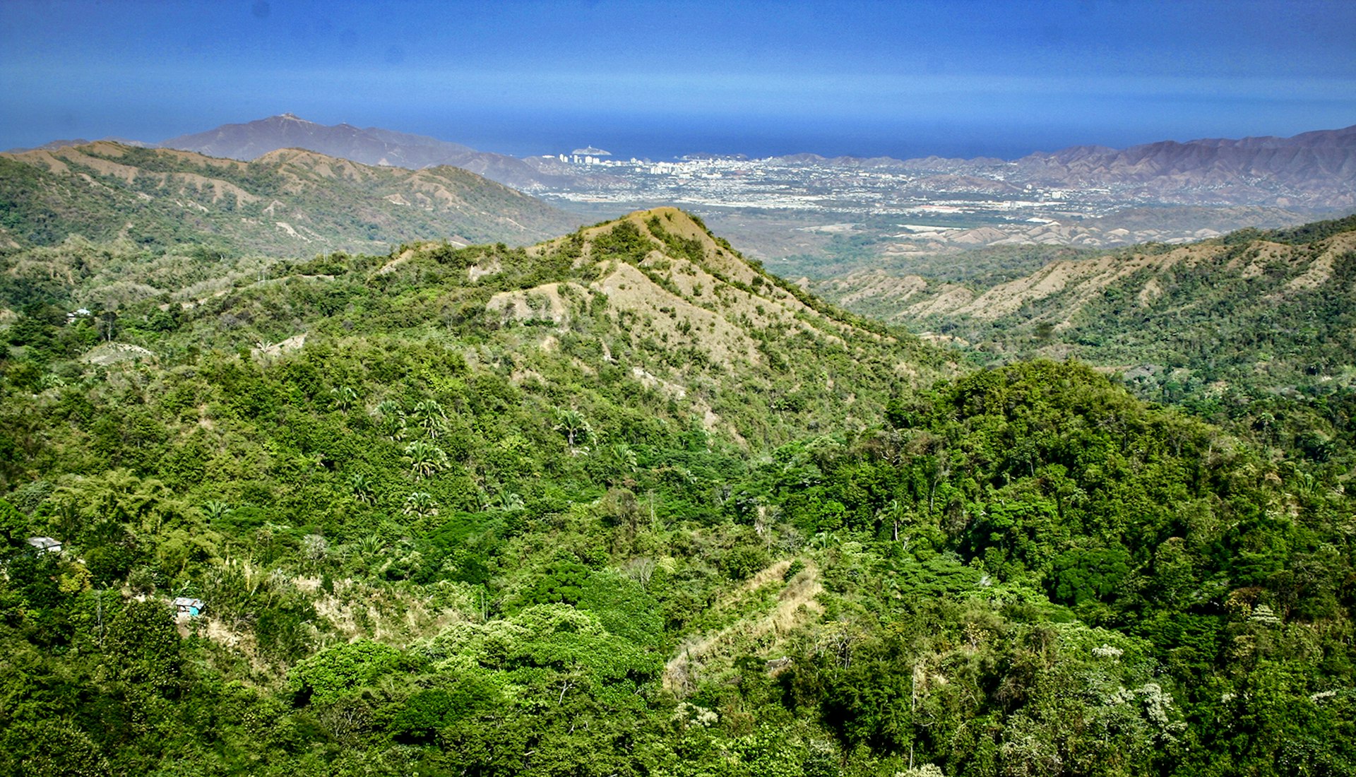 A view of green hills with Santa Marta far away in the background