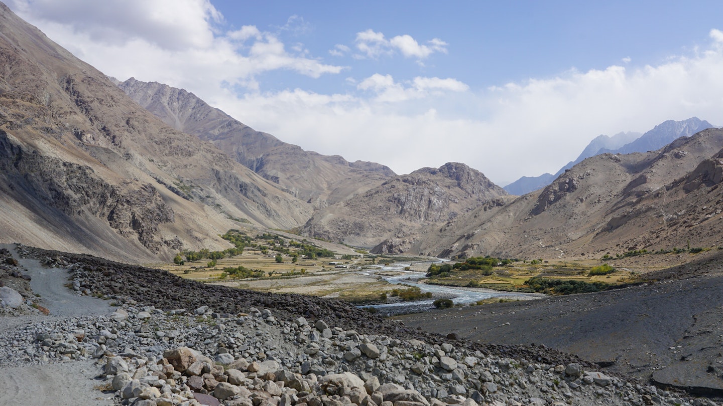 A rock-strewn landscape gives way to a river running through a dry mountain valley