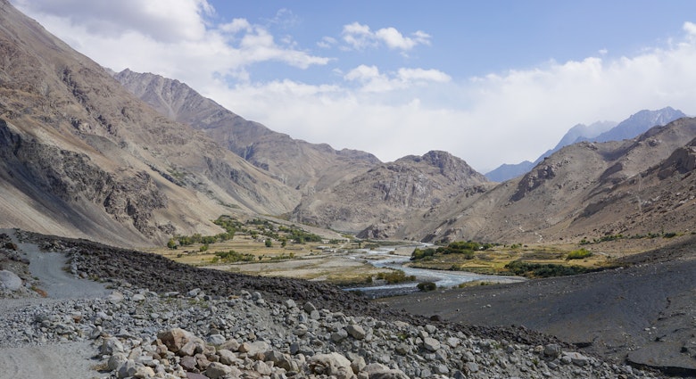 A rock-strewn landscape gives way to a river running through a dry mountain valley
