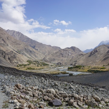 A rock-strewn landscape gives way to a river running through a dry mountain valley