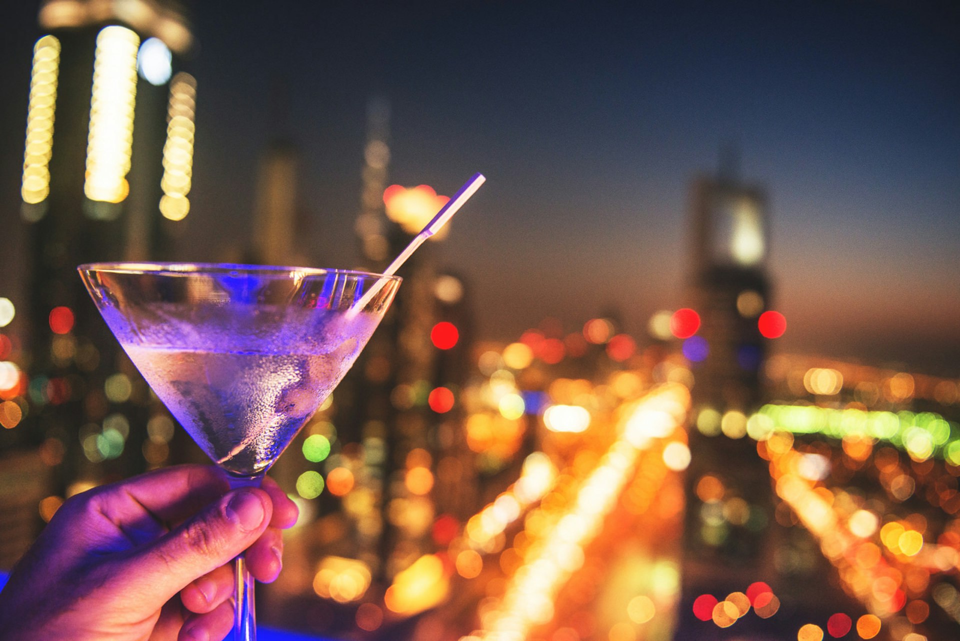 Cocktail in front of nighttime skyline, Dubai, United Arab Emirates