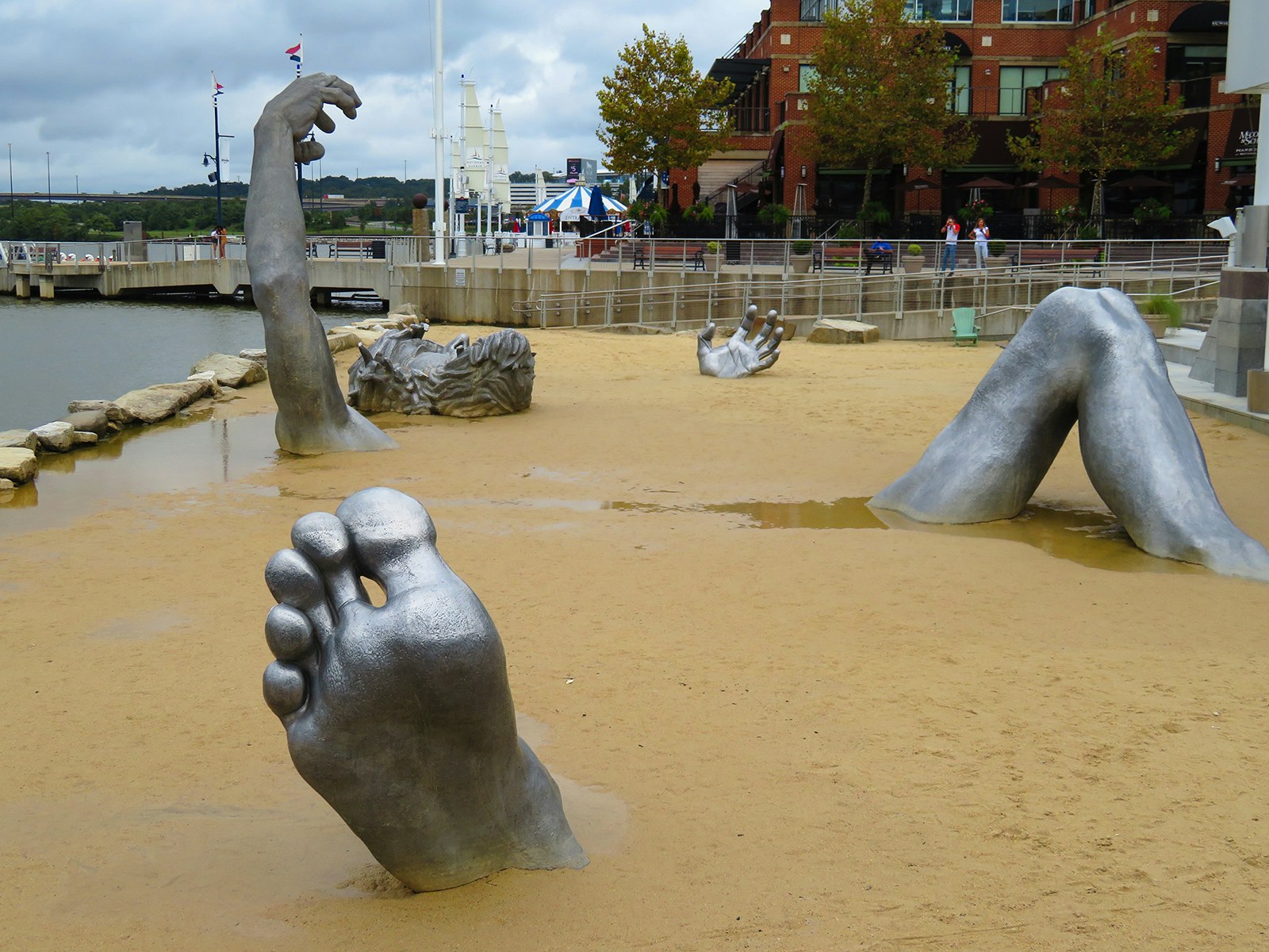 An aluminum sculpture of a man buried under the sand 