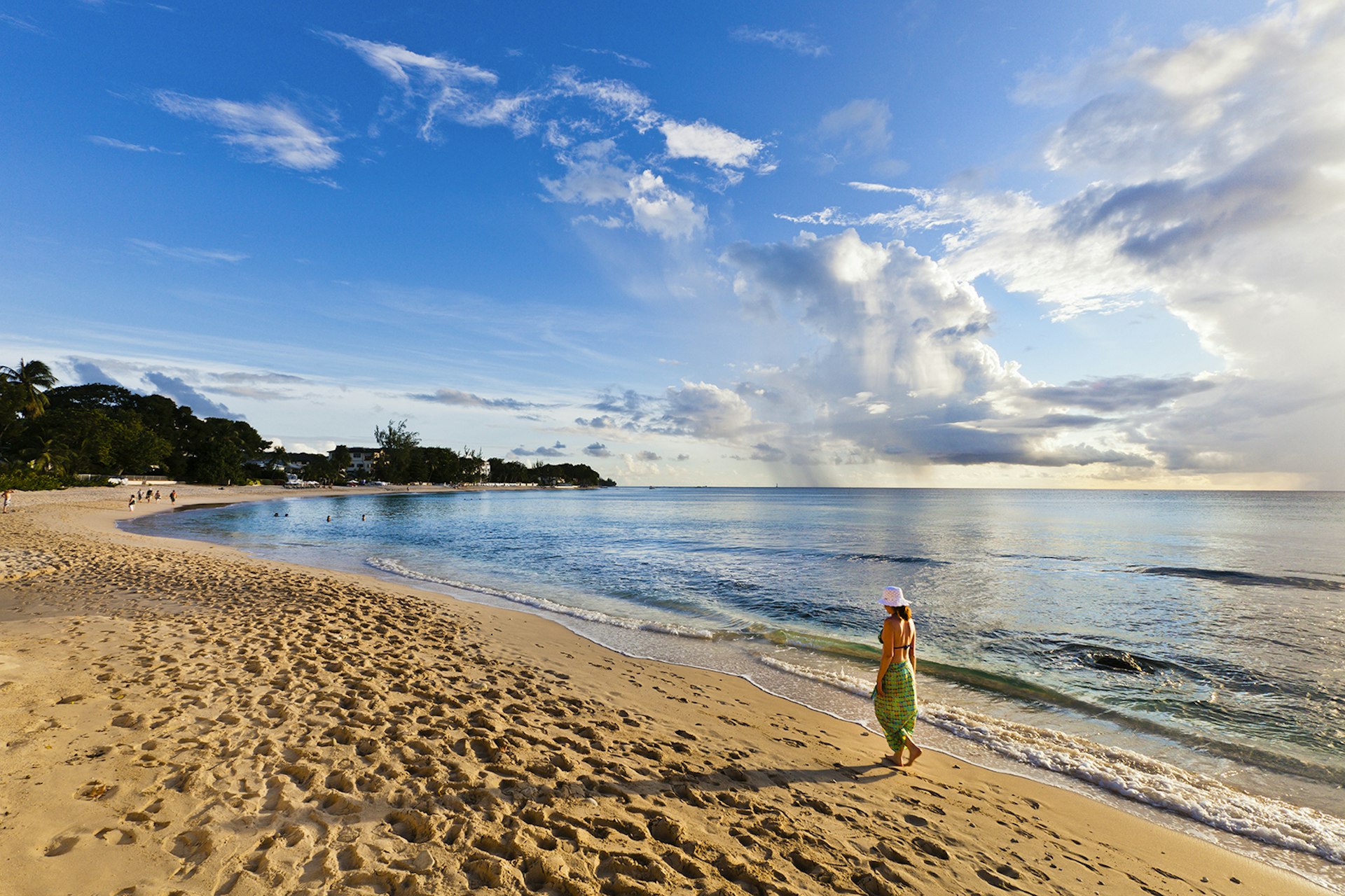 Woman walking on the beach of Paynes Bay at sunset