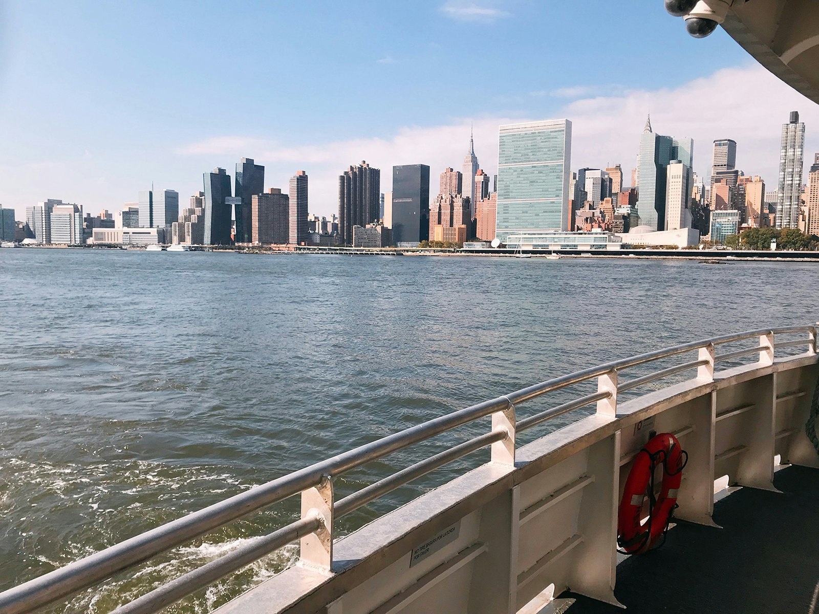 Skyscrapers in East Manhattan, as seen from the Esat River on a sunny day, over the rail of a ferry boat