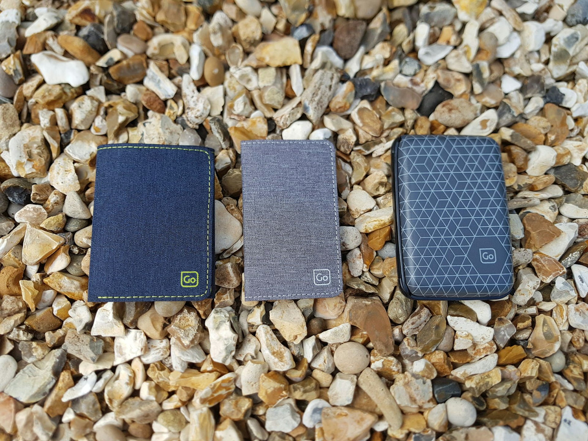 Three Go Travel wallets; one denim, one grey and one with a hard plastic shell