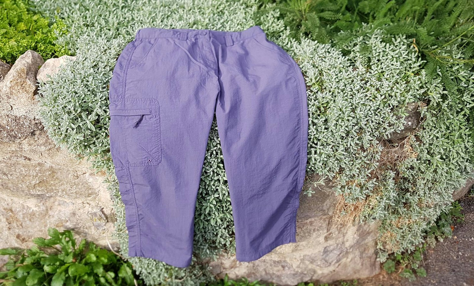 A pair of purple Explore Capris three-quarter length trousers draped over a wall
