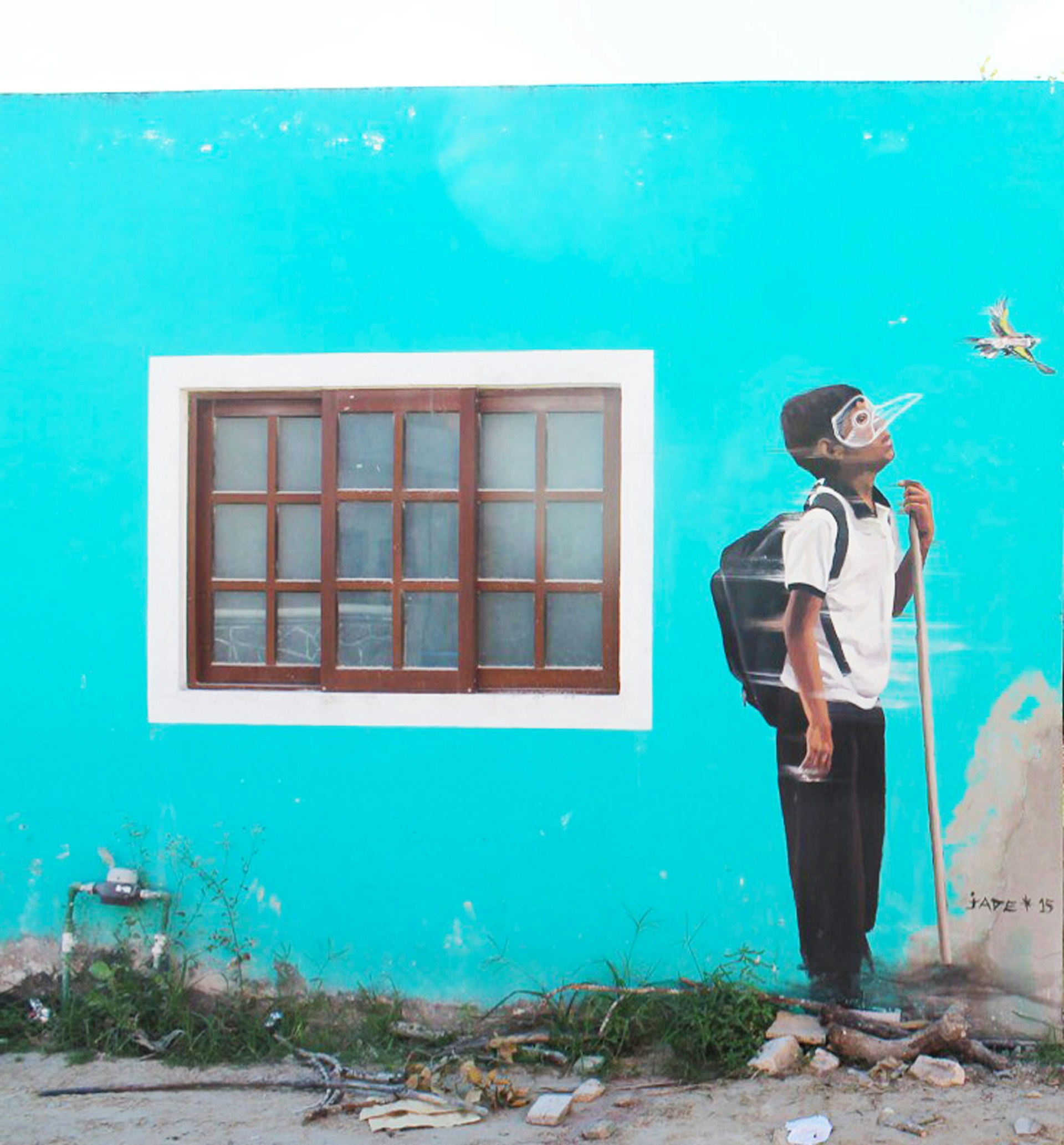 a vivid mural of a boy in a bird mask staring at the sky is painted on the side of a building