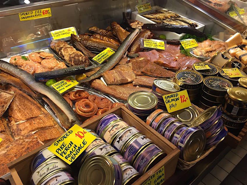 A glass case displaying tins of smoked salmon and a variety of market fish