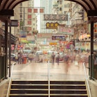 Blurred motion of people going down the stairs of underground crossing with numerous Chinese signs in the background