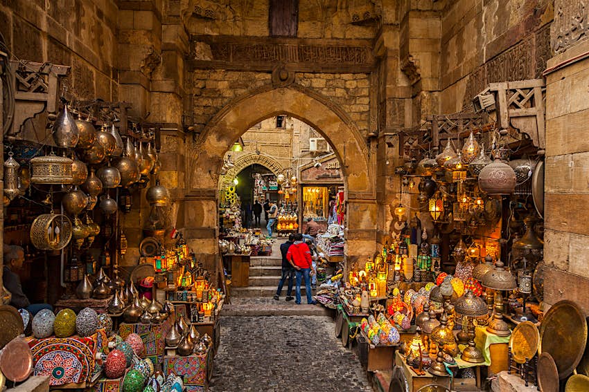 Lamps line the walls on either side of the path through the narrow market alleyway