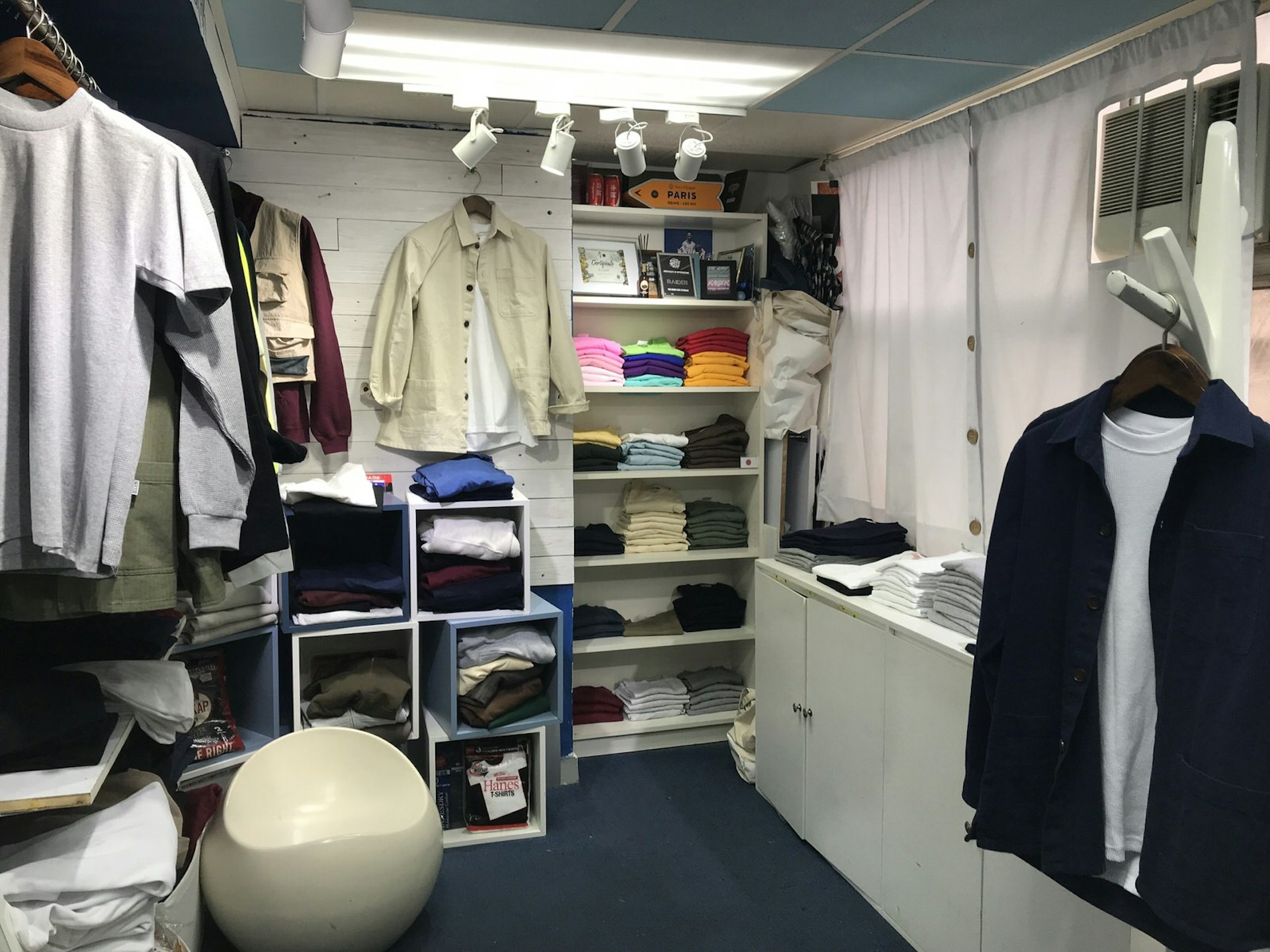 A windowless room with white shelves full of clothes and accessories