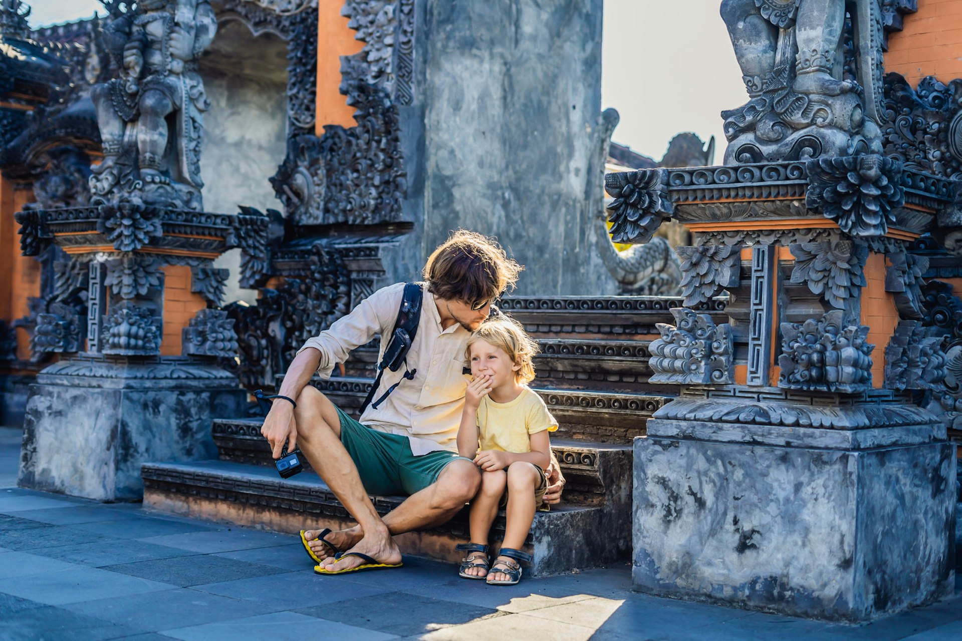 A father an son enjoy an affordable family vacation, on the steps of a temple Bali