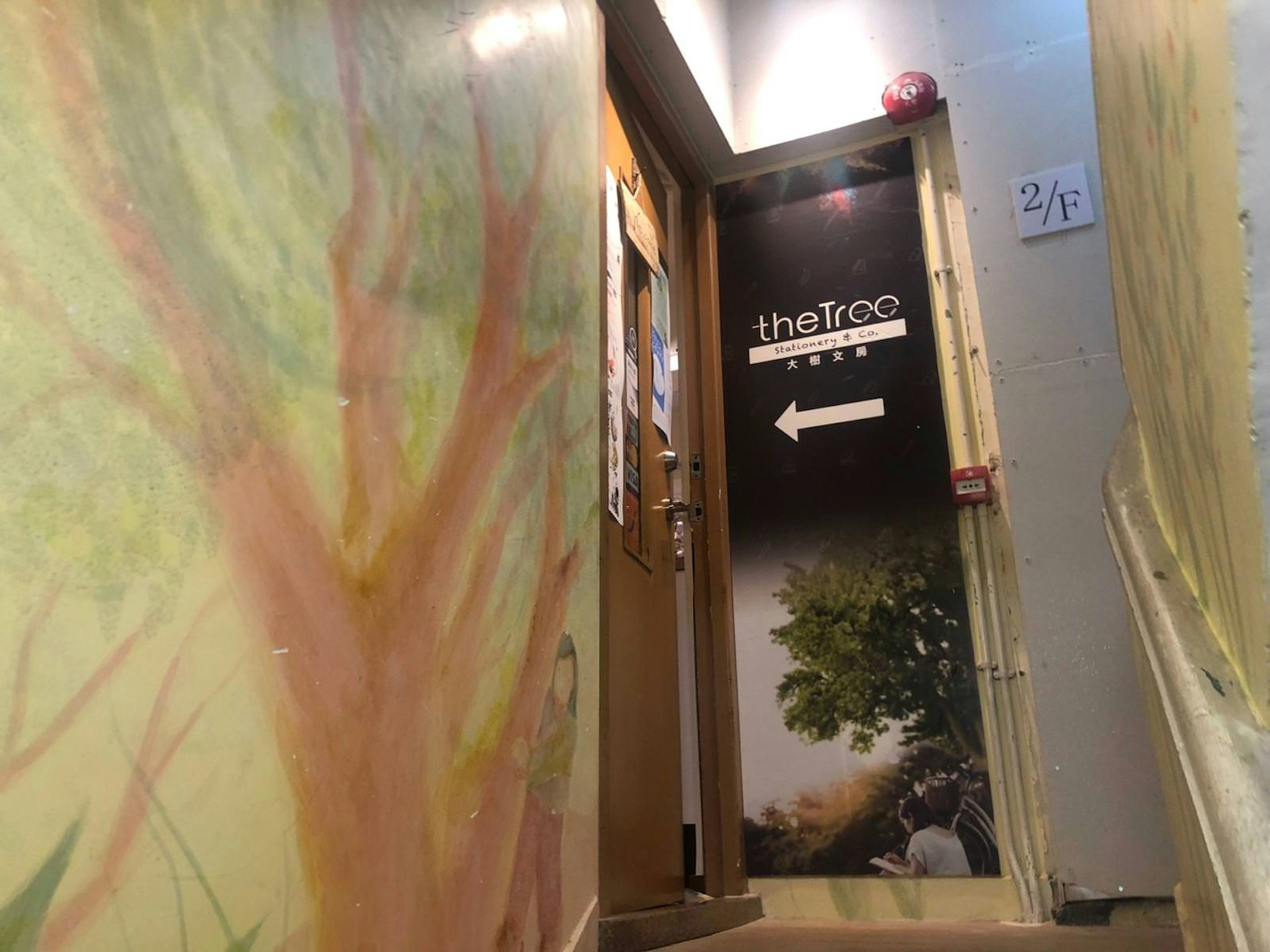 A stairwell with a mural of a tree and the Tree Stationery sign denoting entrance to the shop