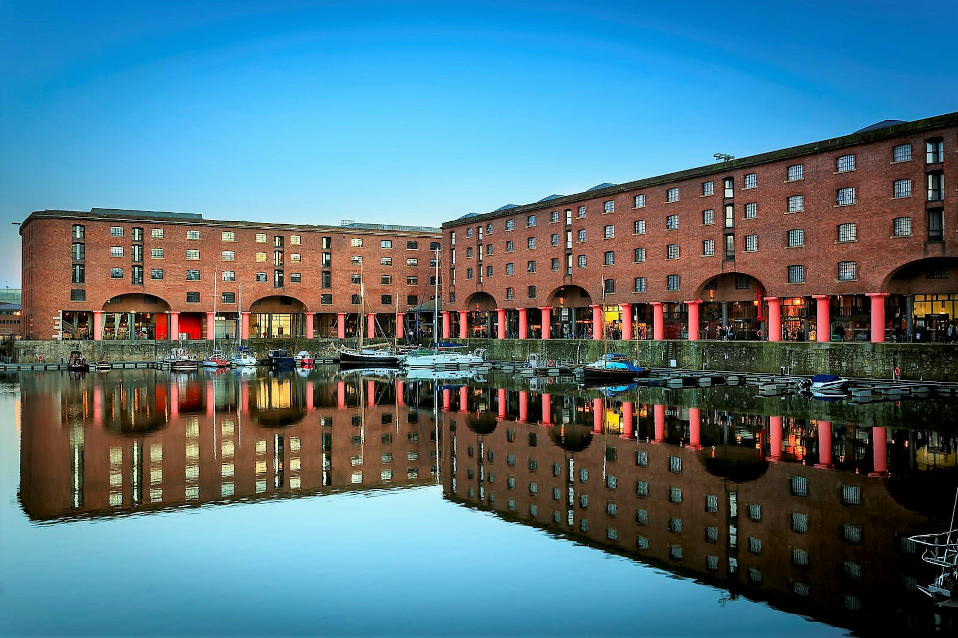 Albert Dock, Liverpool. The red-brick building is reflected in the glassy water of the dock. 