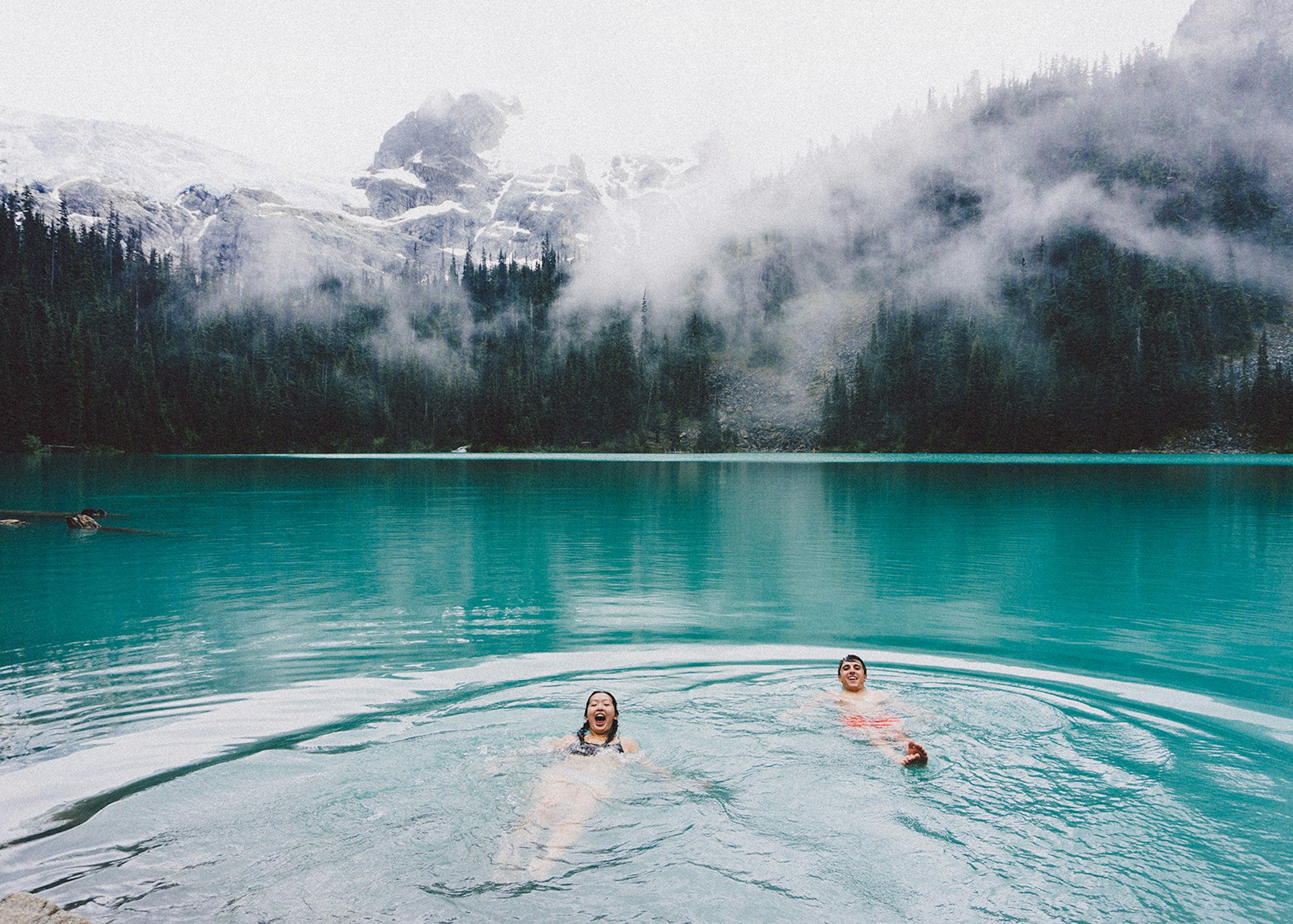 Couple swimming in a lake with mountains in the background